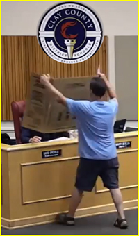 Parent's microphone turned off by School Board so he takes tri-fold sign of pronographic language found in school library books up to a School Board member.